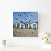 english seaside blue skies and beach huts quadratische wanduhr (Zuhause)