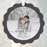 Erste Weihnachten Verlobte Custom Foto Grau Script Ornament Karte<br><div class="desc">Erinnern Sie sich an Ihre Verlobung mit dieser wunderschönen Schmuckkarte. Der kohlegraue Text lautet "Unser erstes Weihnachtsfest verlobt", mit dem Wort "verlobt" in eleganter Handschrift mit Schnörkeln vor und nach. Ersetzen Sie das Beispielbild durch Ihr Lieblings-Foto, und fügen Sie Ihre Namen und das Jahr hinzu. Mithilfe eines Farbverlaufsefilters wird der...</div>