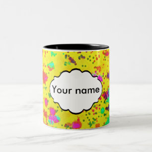 Farbspritze auf gelbem Hintergrund Zweifarbige Tasse