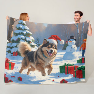 Finnischer Lapphund läuft durch Schnee mit Weihnac Fleecedecke