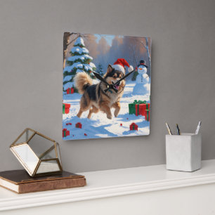Finnischer Lapphund läuft durch Schnee mit Weihnac Quadratische Wanduhr
