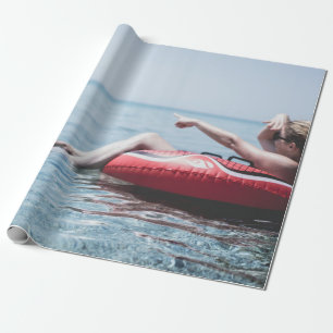 Frau auf einem aufblasbaren Schwimmer im Ozean, de Geschenkpapier