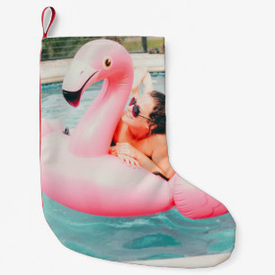 Frau auf rosa aufblasbarem Flamingo im Außenpool Kleiner Weihnachtsstrumpf