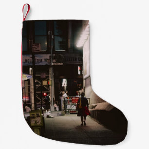 FRAU IN SCHWARZ UND ROT DRESS ZU FUSS NEBEN BROWN  KLEINER WEIHNACHTSSTRUMPF