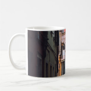FRAU IN WEISSEN SHIRT- UND SCHWARZPANTEN, DIE AUF KAFFEETASSE