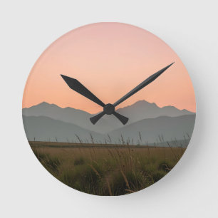 Friedliche rosa Sonnenuntergangsberge wilde Grasla Runde Wanduhr