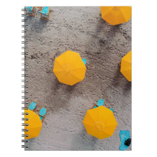 Fünf gelbe Sonnenschirme am Tag auf Sand Notizblock