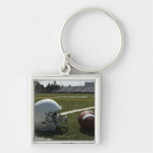 Fußball und Football-Helm auf Fußballplatz Schlüsselanhänger