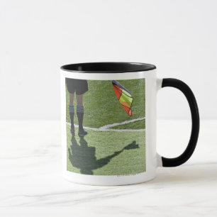Fußballreferent, der Flagge hält Tasse