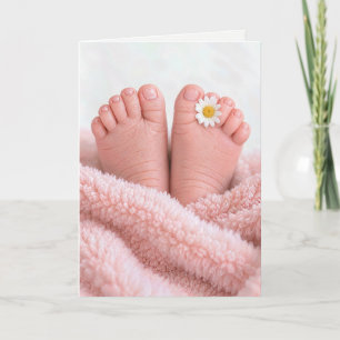 Füße eines Babymädchens mit einer weißen Margerite Karte