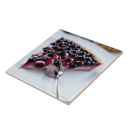 Gabel, die Heidelbeerkuchen auf Platte schneidet Fliese (Seite)