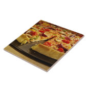 Gemüsepizza geschnitten auf schwarzer Wanne auf Fliese (Seite)