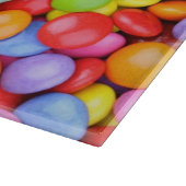 Gestreifter Lutscher und mehrfarbige Smarties Schneidebrett (Ecke)