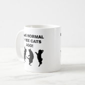 Gewöhnliche drei Katzen sind vor lustiger Umarmung Kaffeetasse (Vorderseite Links)