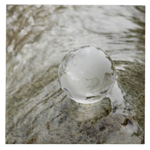Glaskugel auf dem Wasserstrom Fliese