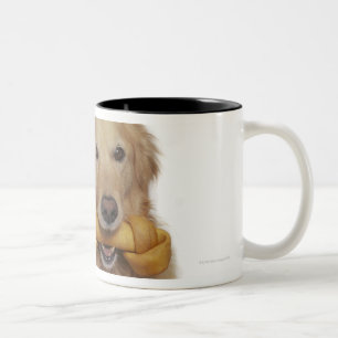 Golden retriever-Hund, der Knochen im Mund hält Zweifarbige Tasse