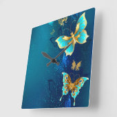 Goldene Schmetterlinge auf einem blauen Hintergrun Quadratische Wanduhr (Winkel)
