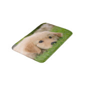 Goldener Retriever-niedlicher Welpe, der die Badematte (Schrägansicht)