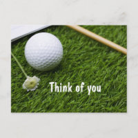 Golfball mit einer kleinen Blume auf Gras denken S