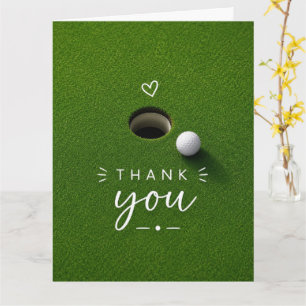 Golfball neben Loch auf grünem Gras Danke Karte