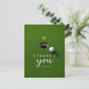 Golfball neben Loch auf grünem Gras Danke Postkarte