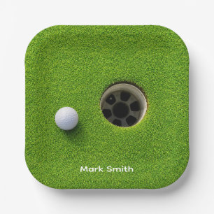 Golfball neben Loch auf grünem Rasen Golfplatz Pappteller