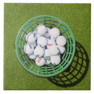 Golfbälle in einem Korb, der auf kurzem Grün sit Fliese
