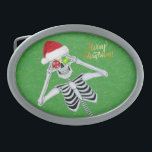Goofy Skeleton Ornaments Weihnachtsmannmütze auf G Ovale Gürtelschnalle<br><div class="desc">Dieser Gürtelschnalle hat ein goofy skelett,  das zwei glänzende Weihnachtsball-Ornamente mit einer roten Weihnachtsmannmütze auf einem grünen Hintergrund mit Goldflecken aufhält. Frohe Weihnachtstexte in Gold.</div>