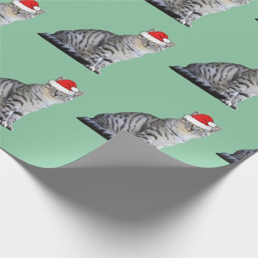 Graue, weiße Katze mit einer Weihnachtsmannmütze Geschenkpapier (Ecke)