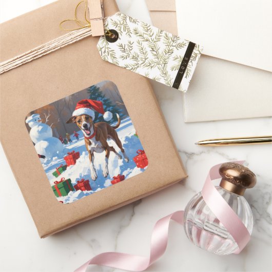Greyhound läuft im Schnee mit Weihnachtshut Quadratischer Aufkleber (Schenken)