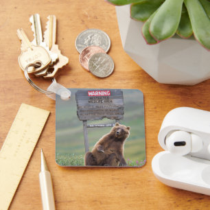 Grizzlybär spielt mit Schild Schlüsselanhänger