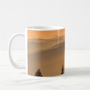 GRÜNE KIEFERNBÄUME AM BERG WÄHREND DES TAGES KAFFEETASSE