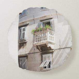 GRÜNE TOPFPFLANZE AUF BRAUNEM BETONHAUSBALKON RUNDES KISSEN