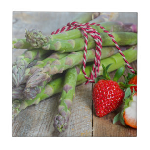 Grüner Spargel mit Erdbeeren auf Holz Fliese