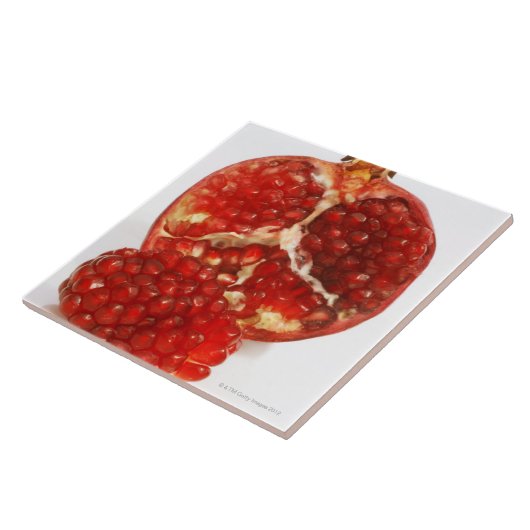 Hälfte ein reifer Granatapfelschnitt, zum das Fliese (Seite)