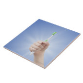 Hand, die Zahnbürste hält Fliese (Seite)