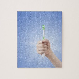 Hand, die Zahnbürste hält Puzzle