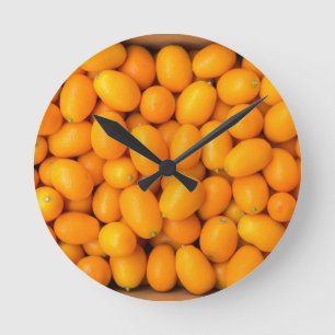 Heap of orange kumquats in cardboard box runde wanduhr