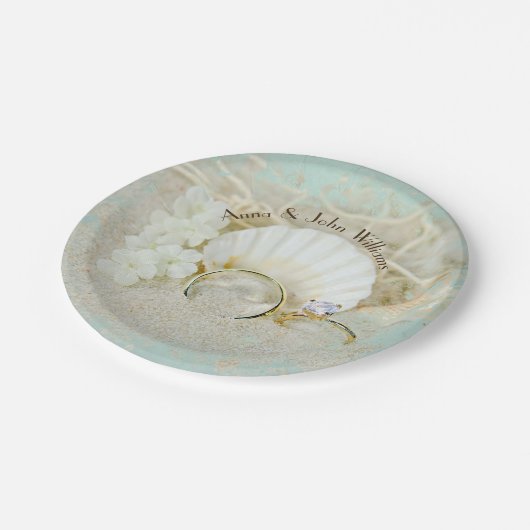 Hochzeitsringe und Muscheln im Sand mit Netz Pappteller (Schrägansicht)