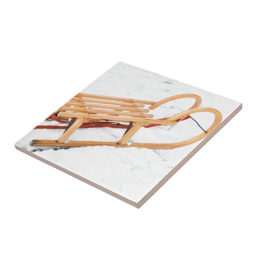 Hölzerner Kinderschlitten im Winterschnee Fliese (Seite)