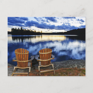 Holzstühle bei Sonnenuntergang am See Postkarte