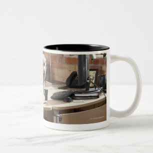 Hund, der am Schreibtisch sitzt Zweifarbige Tasse