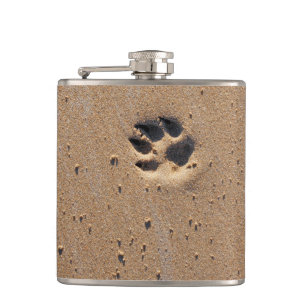 Hundepete druckt auf einem Sandstrand Flachmann