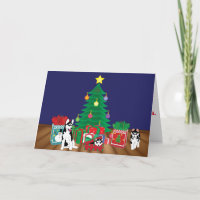 Huskies, der unter der Weihnachtsbaum-Karte spielt