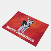Husky in Weihnachtsmannmütze auf Rot Fußmatte (Schrägansicht)