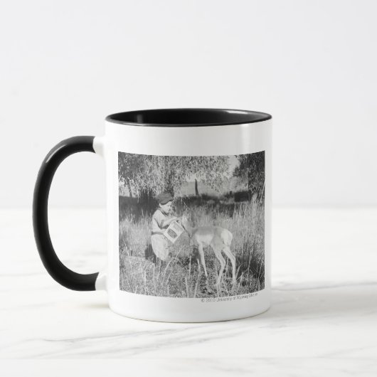 Junge, der Antilope füttert Tasse (Links)