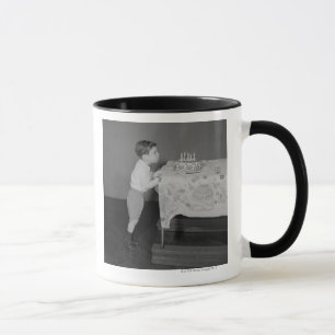 Junge, der heraus Kerzen durchbrennt Tasse