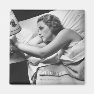 Junge Frau, die auf dem Bett an abstellt Lampe Magnet