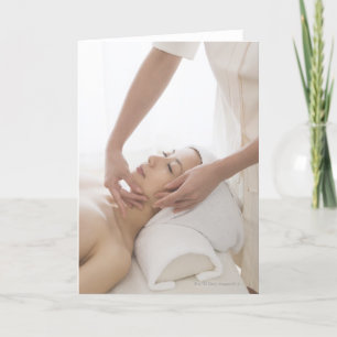Junge Frau, die Gesichtsmassage hat Karte