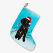 Junge Hündin sitzt im Schnee mit Weihnachtsmannmüt Kleiner Weihnachtsstrumpf (Vorderansicht (hängend))